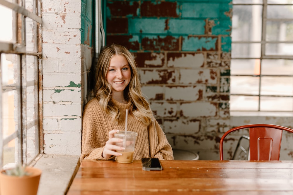 a woman sitting at a table with a drink