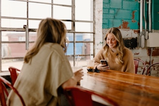 a woman sitting at a table with a cell phone