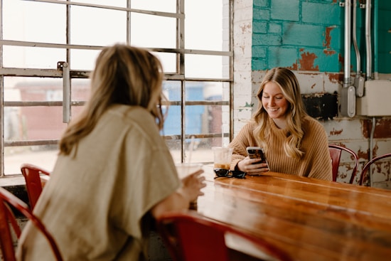 a woman sitting at a table with a cell phone