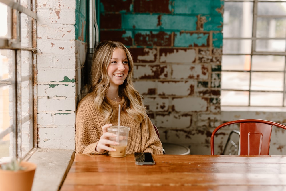 a woman sitting at a table with a drink