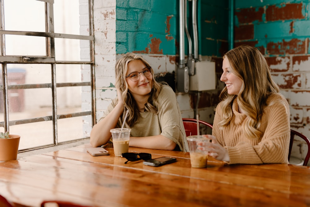 a couple of women sitting at a wooden table