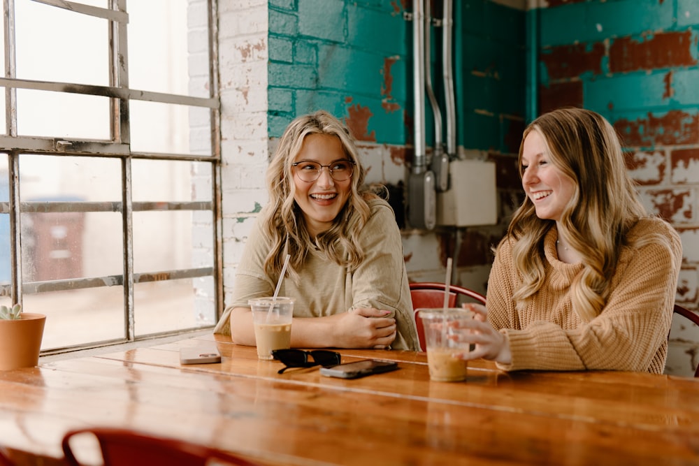 two women sitting at a table with drinks