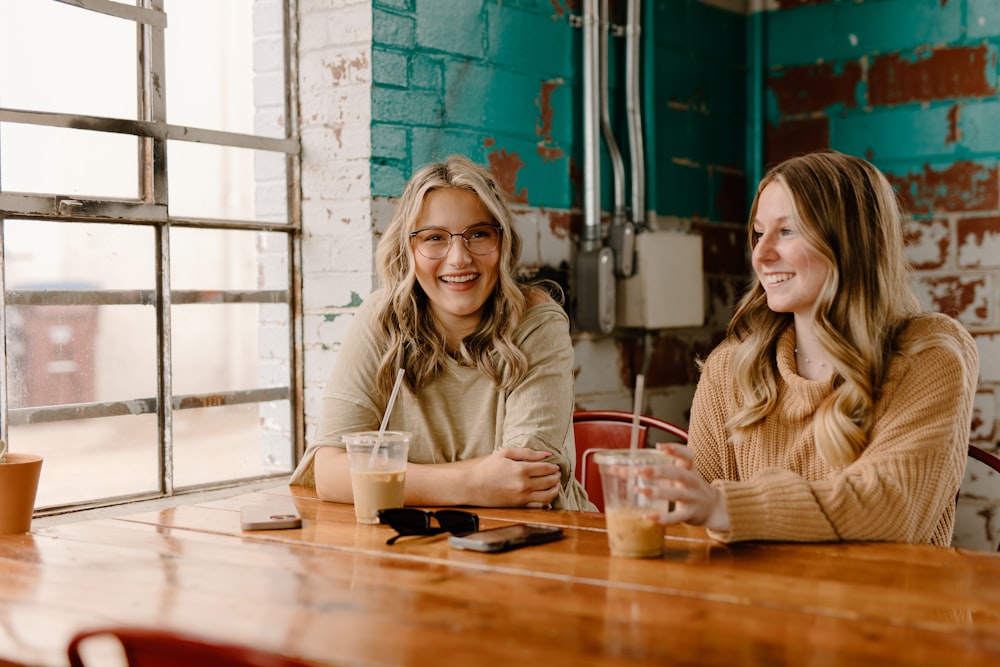 two women sitting at a table with drinks