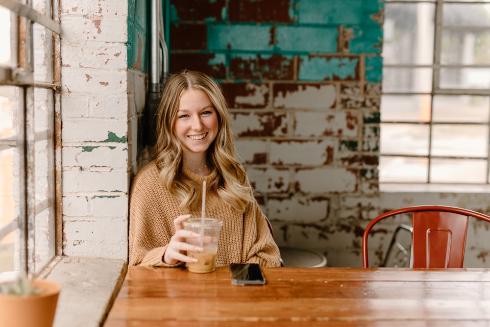 a woman sitting at a table holding a glass