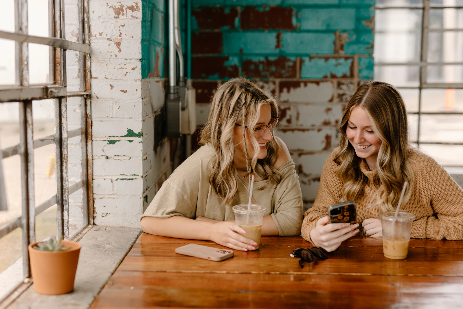 Two moms laughing together over a phone