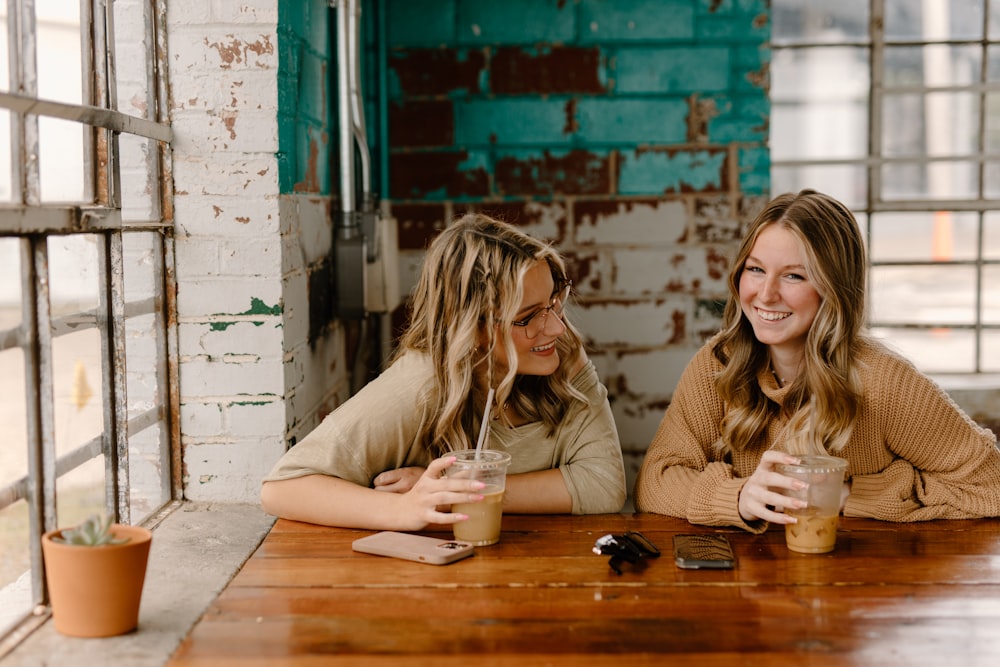 a couple of women sitting at a wooden table