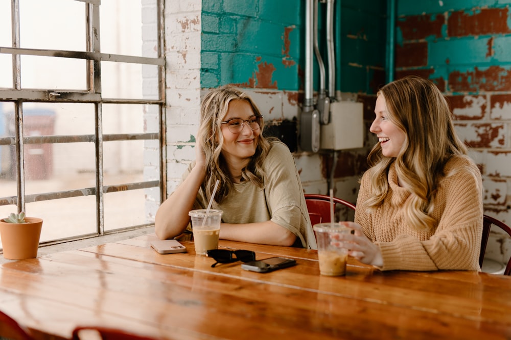 a couple of women sitting at a wooden table