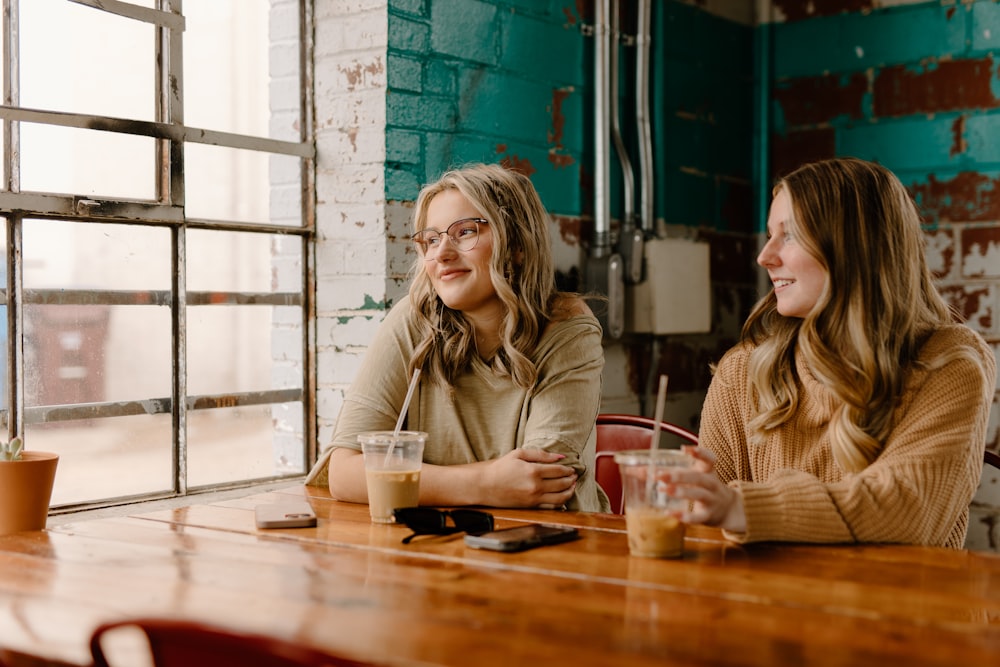 two women sitting at a table with drinks