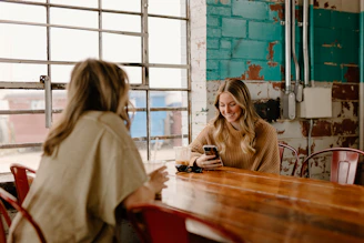 a woman sitting at a table with a cell phone