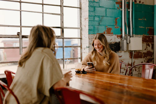 a woman sitting at a table with a cell phone
