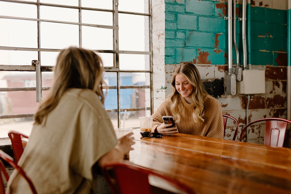 a woman sitting at a table with a cell phone