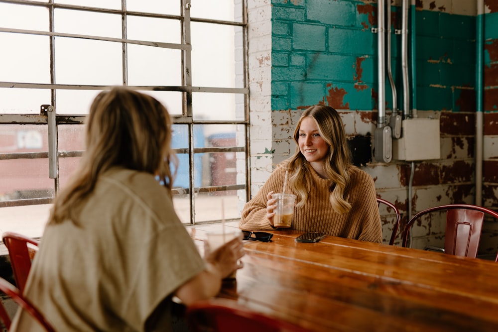 a woman sitting at a table talking to another woman