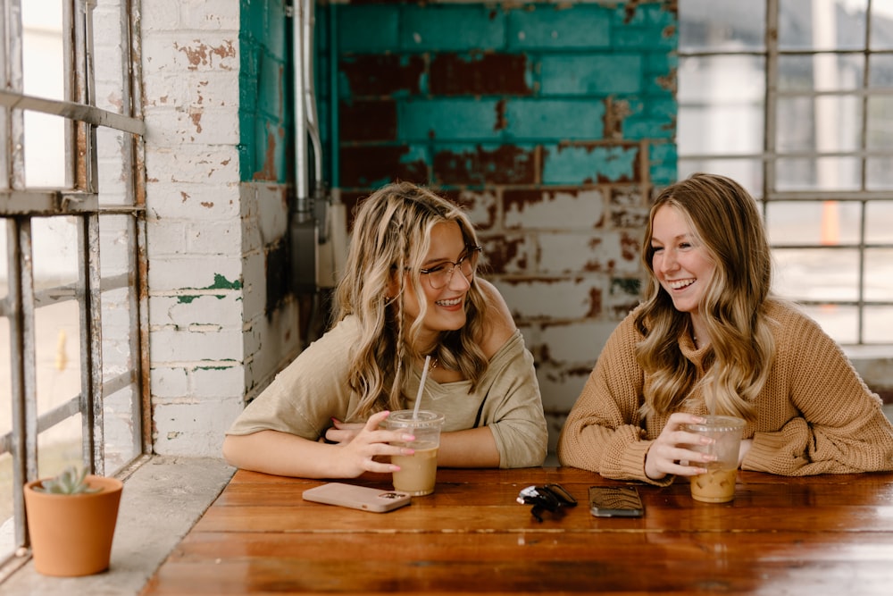 two women sitting at a table with drinks