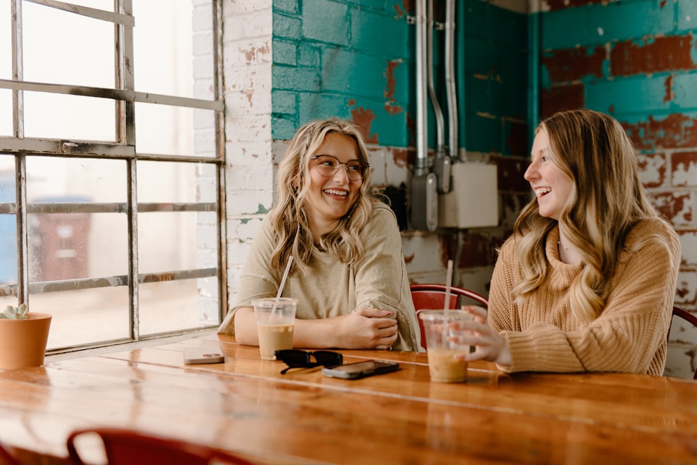 a couple of women sitting at a wooden table