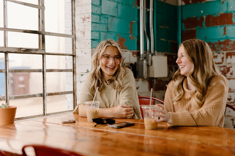 a couple of women sitting at a wooden table