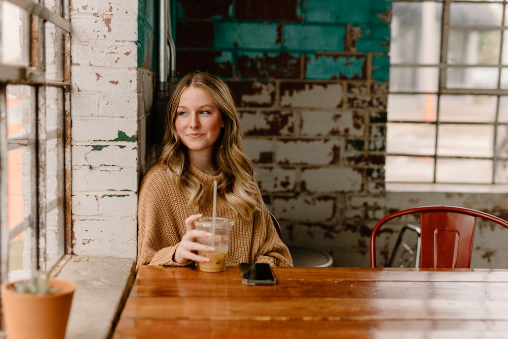 a woman sitting at a table with a drink