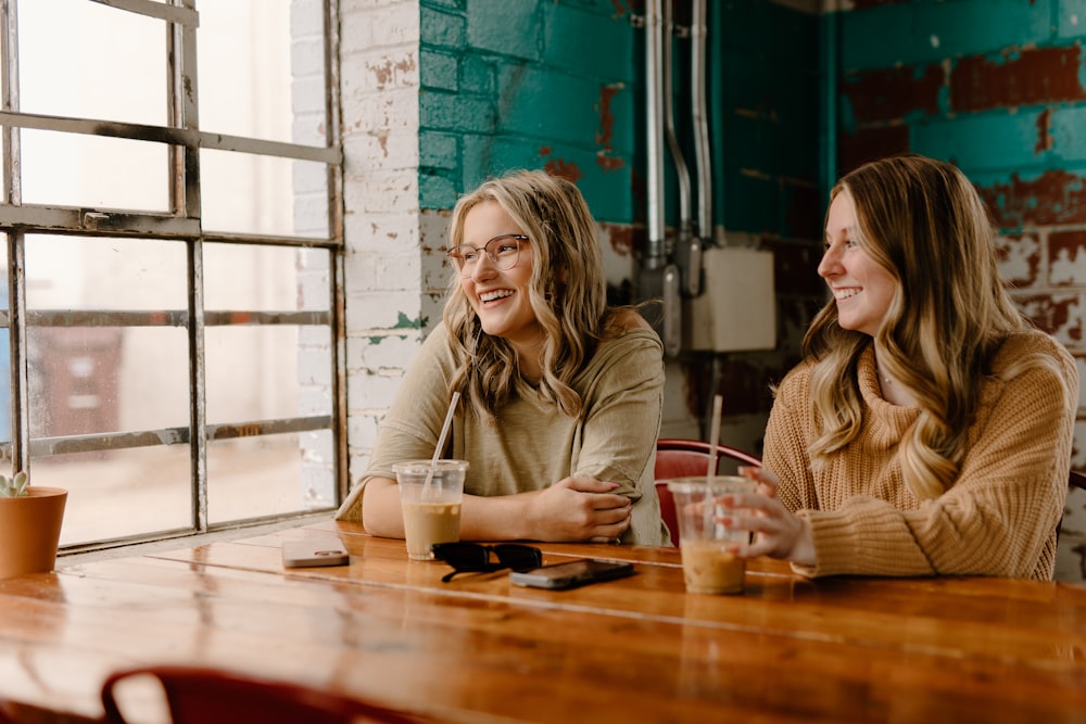 a couple of women sitting at a wooden table