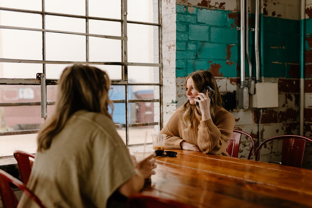 a woman sitting at a table talking on a cell phone