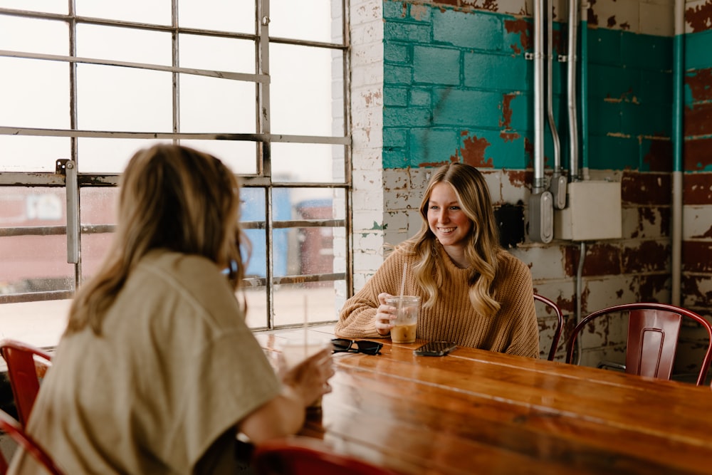 a woman sitting at a table talking to another woman