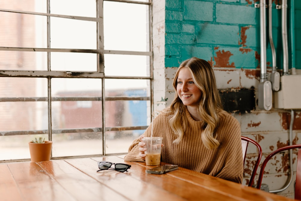 a woman sitting at a table with a drink