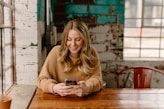 a woman sitting at a table looking at her cell phone