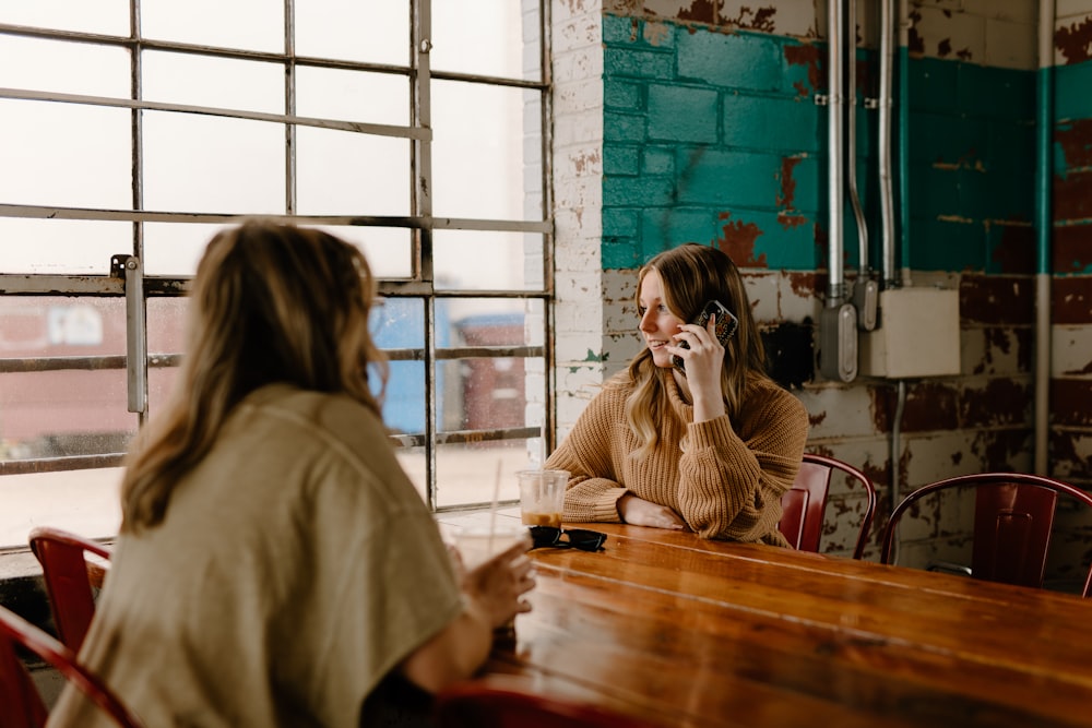 a woman sitting at a table talking on a cell phone