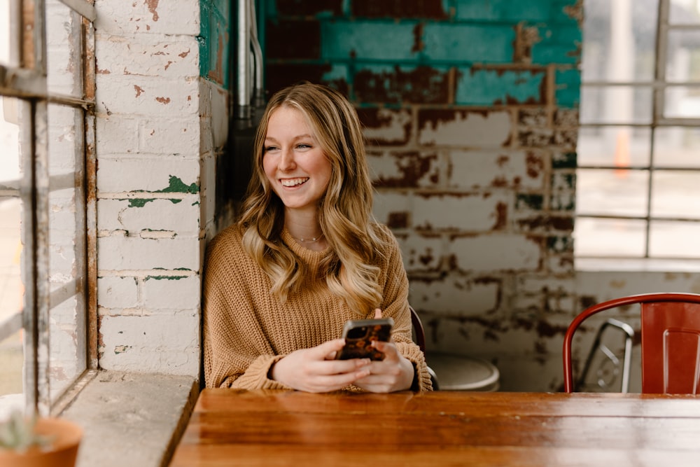 a woman sitting at a table with a cell phone