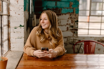 a woman sitting at a table with a cell phone