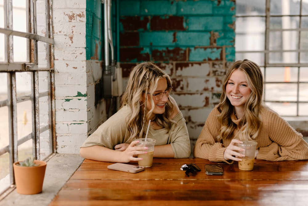 two women sitting at a table with drinks