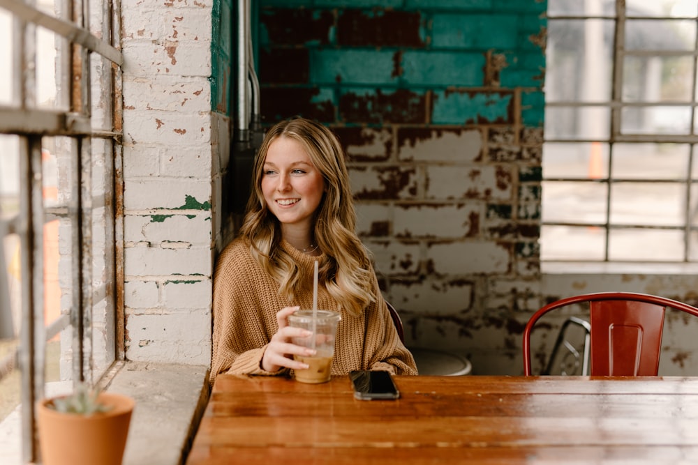 a woman sitting at a table with a drink