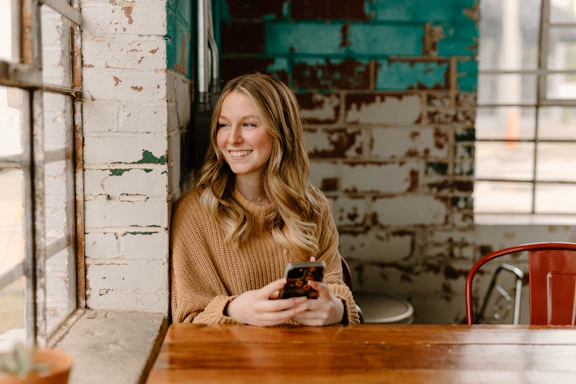 a woman sitting at a table with a cell phone
