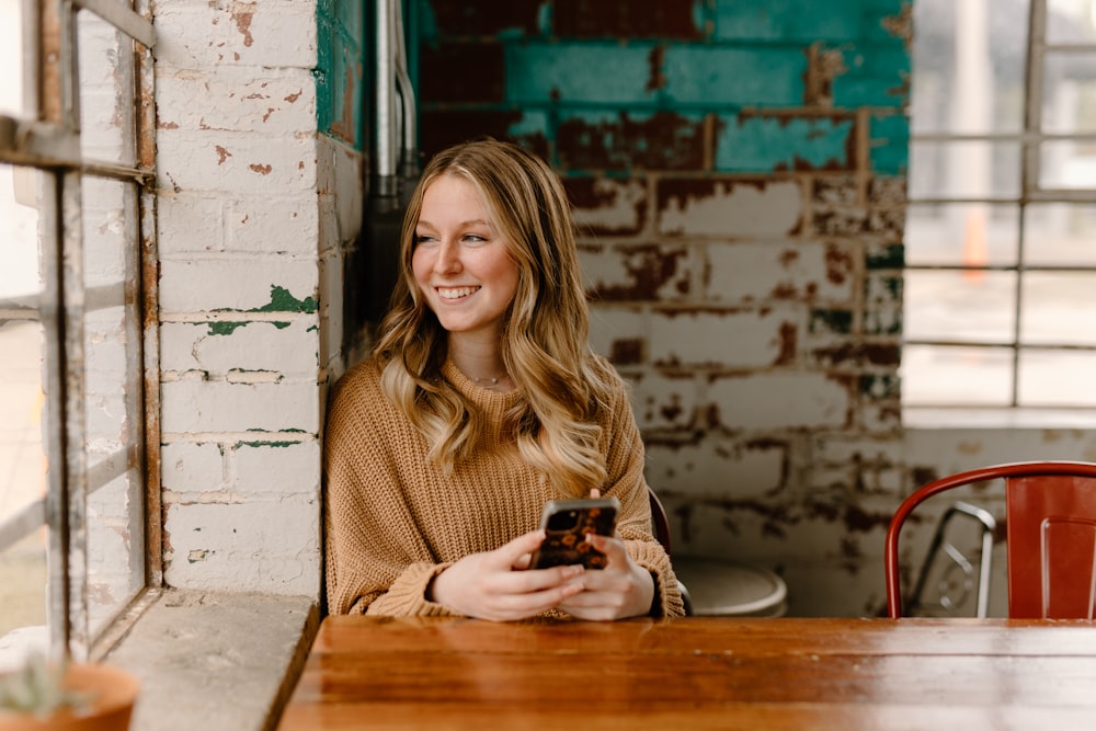 a woman sitting at a table with a cell phone