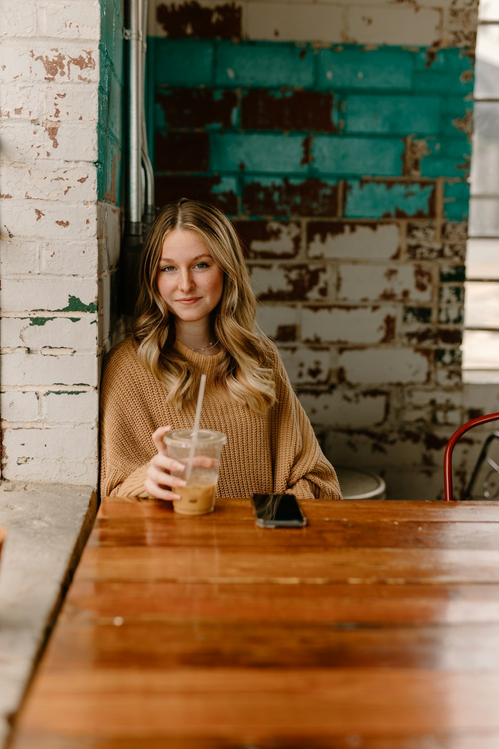 a woman sitting at a table with a drink