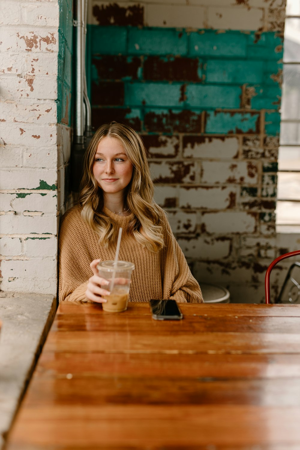 a woman sitting at a table with a drink