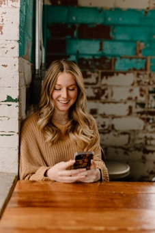 a woman sitting at a table looking at her cell phone