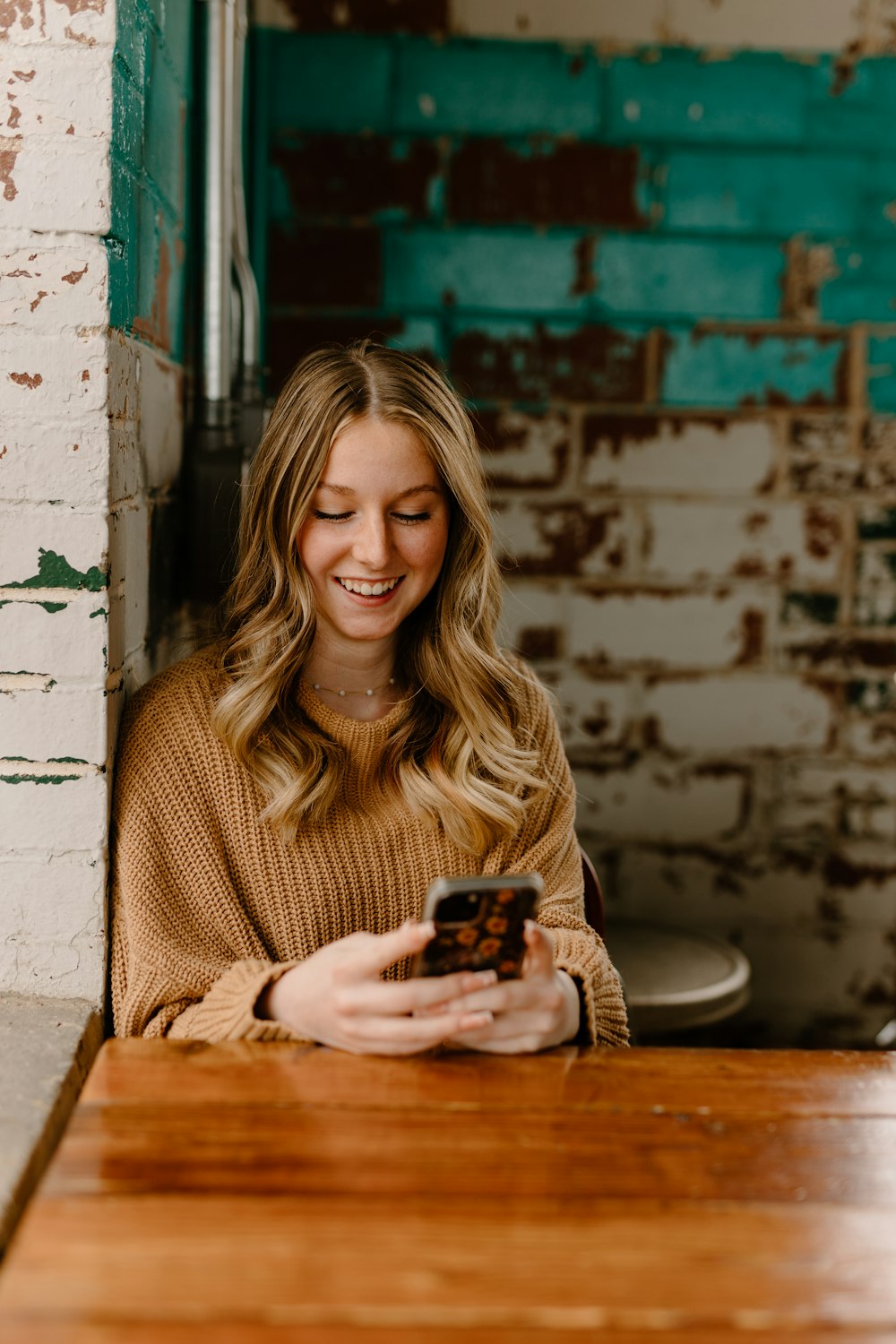 a woman sitting at a table looking at her cell phone