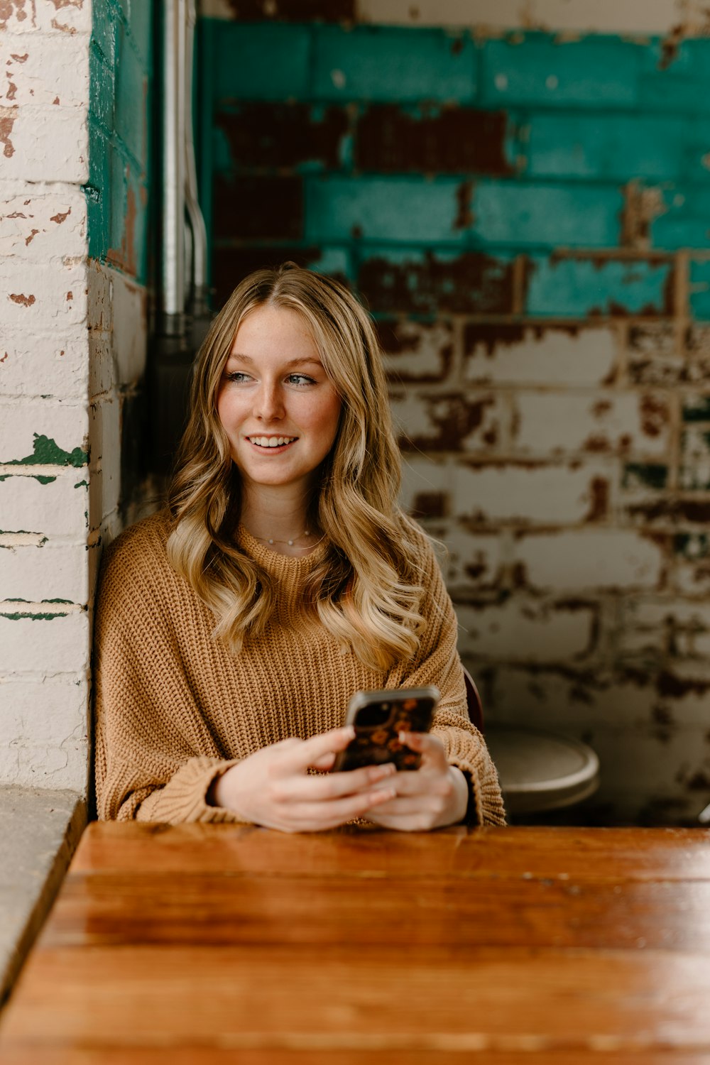 a woman sitting at a table with a cell phone