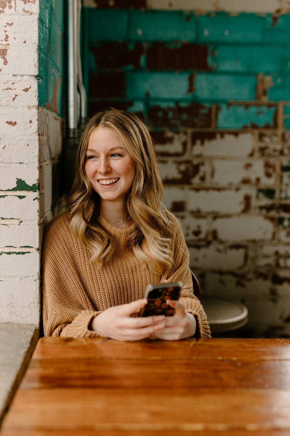 a woman sitting at a table with a cell phone