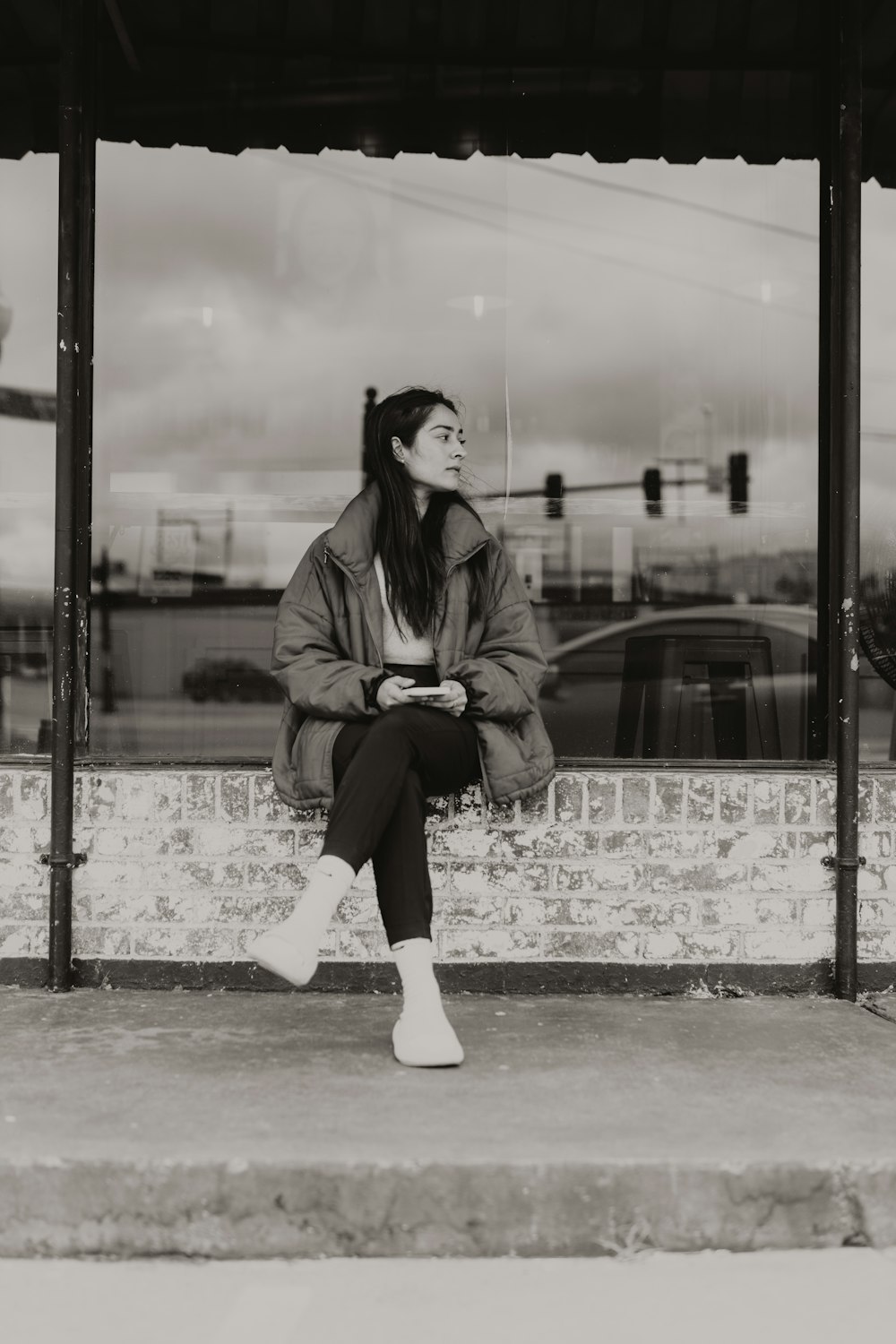 a black and white photo of a woman sitting on a bench