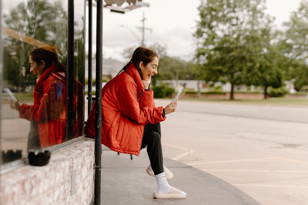 a woman in a red jacket looking at her cell phone