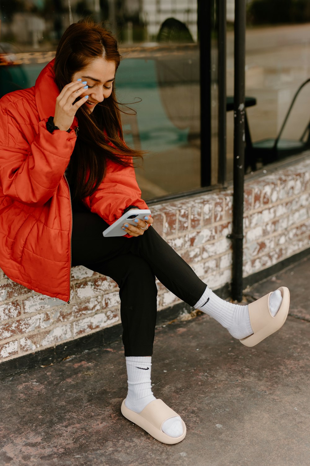 a woman in a red jacket sitting on a window sill