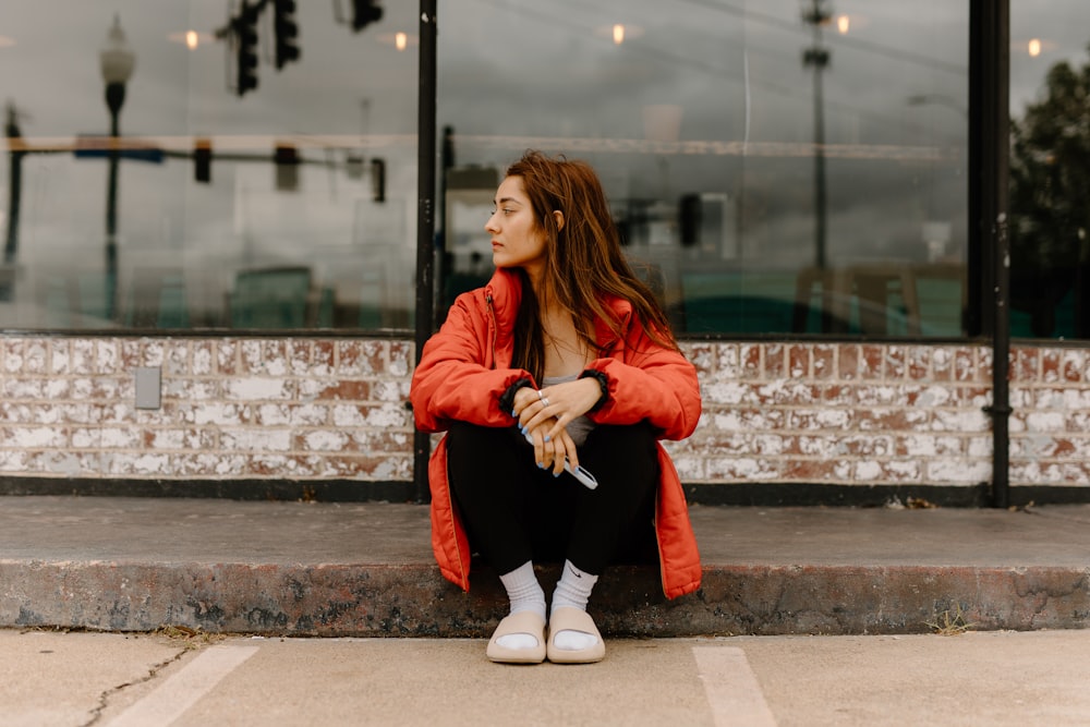 a woman sitting on a curb in front of a building