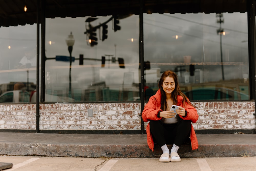 a woman sitting on a curb looking at her cell phone