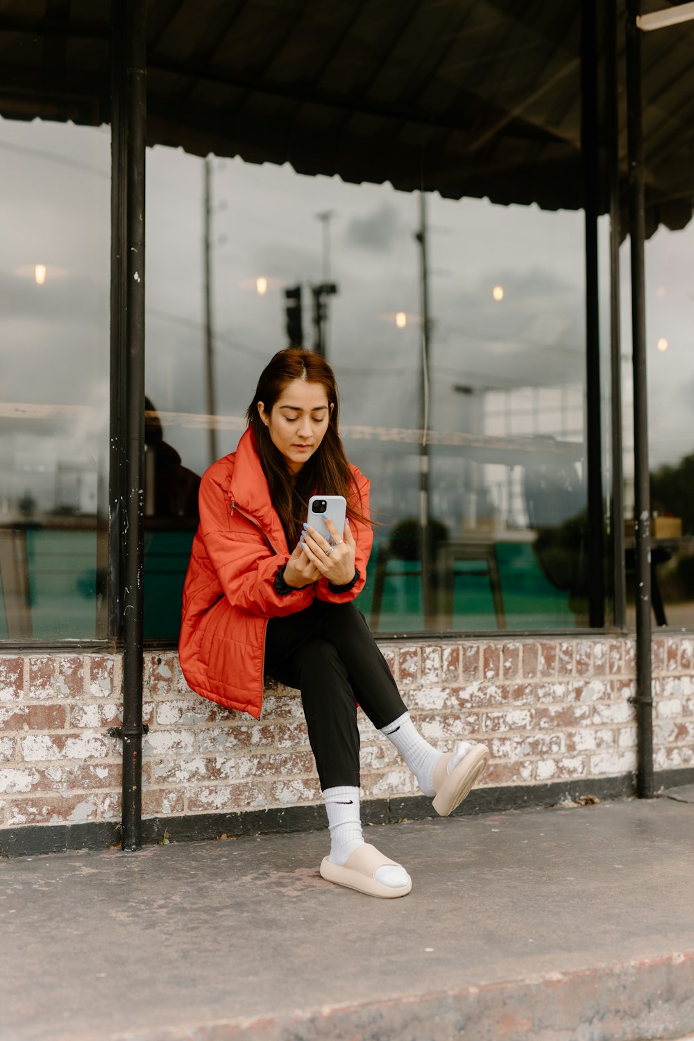 a woman sitting on a ledge looking at her cell phone