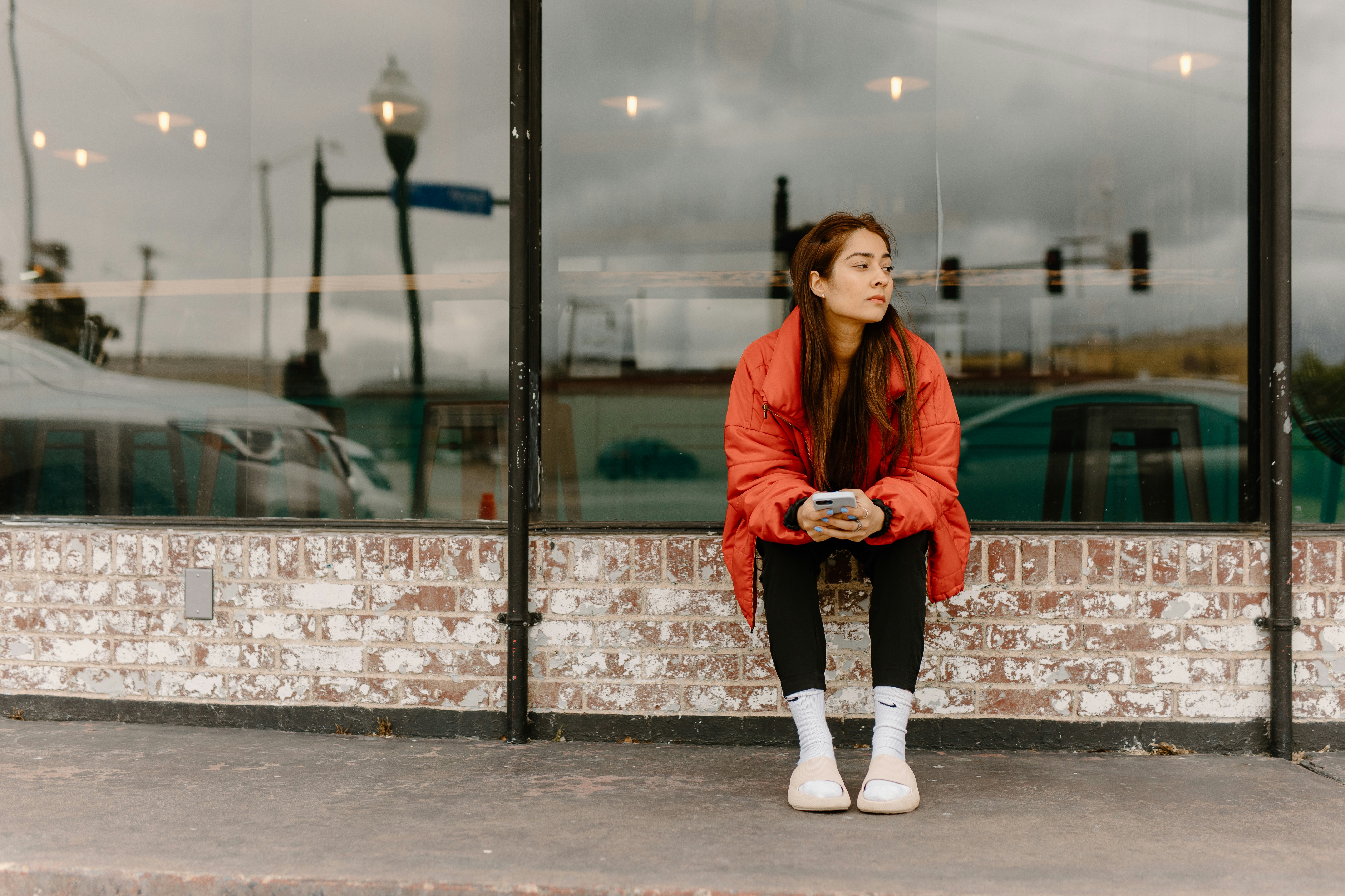 a woman in a red jacket sitting on a brick wall