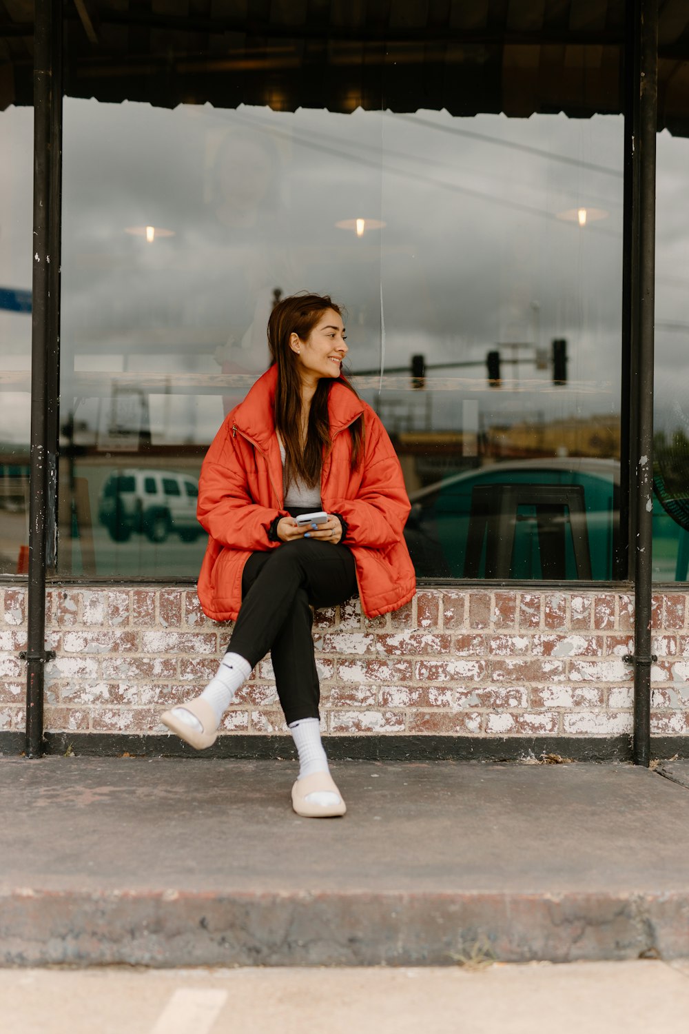 a woman in a red jacket sitting on a bench