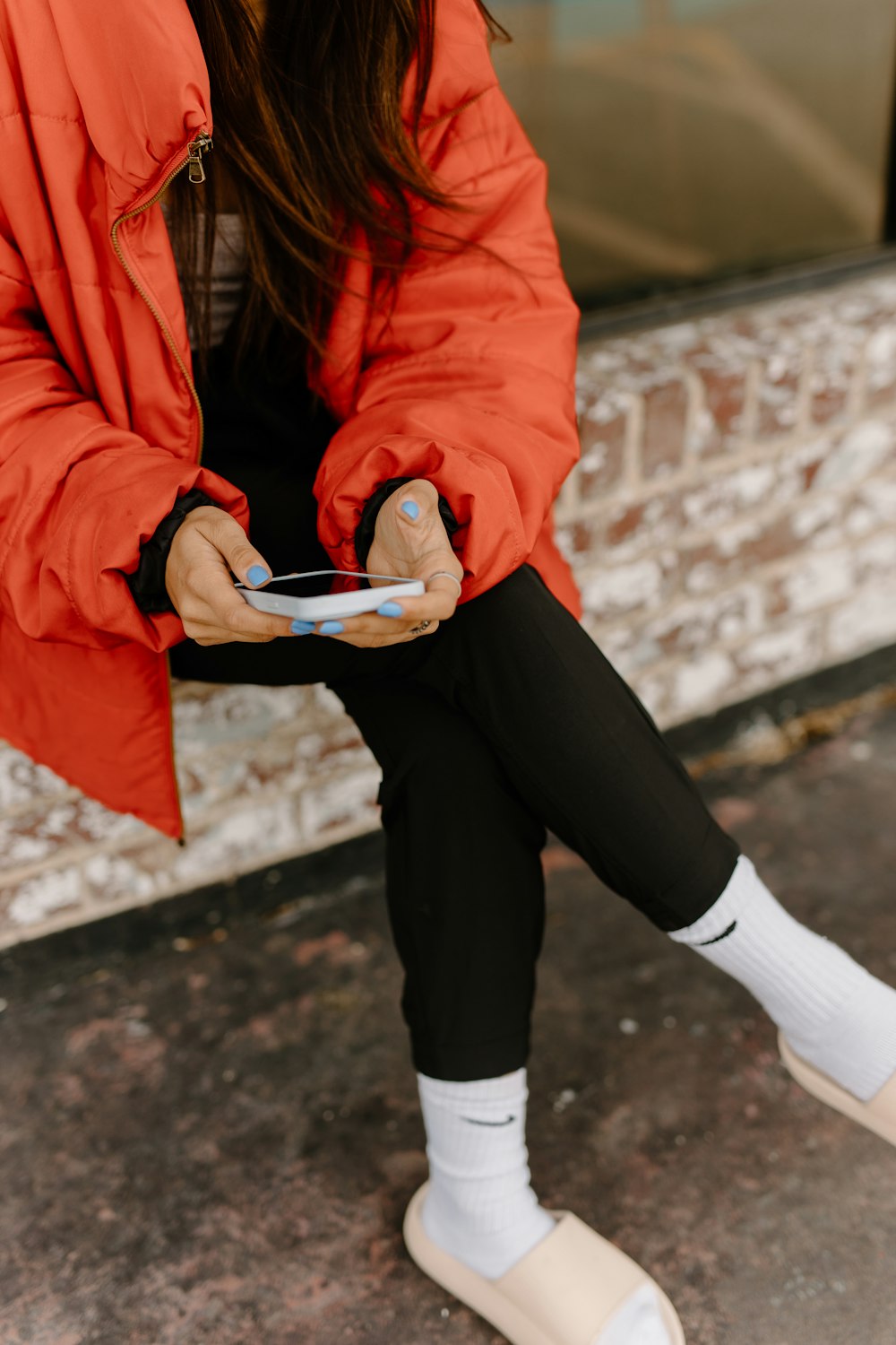 a woman in a red jacket is holding a cell phone