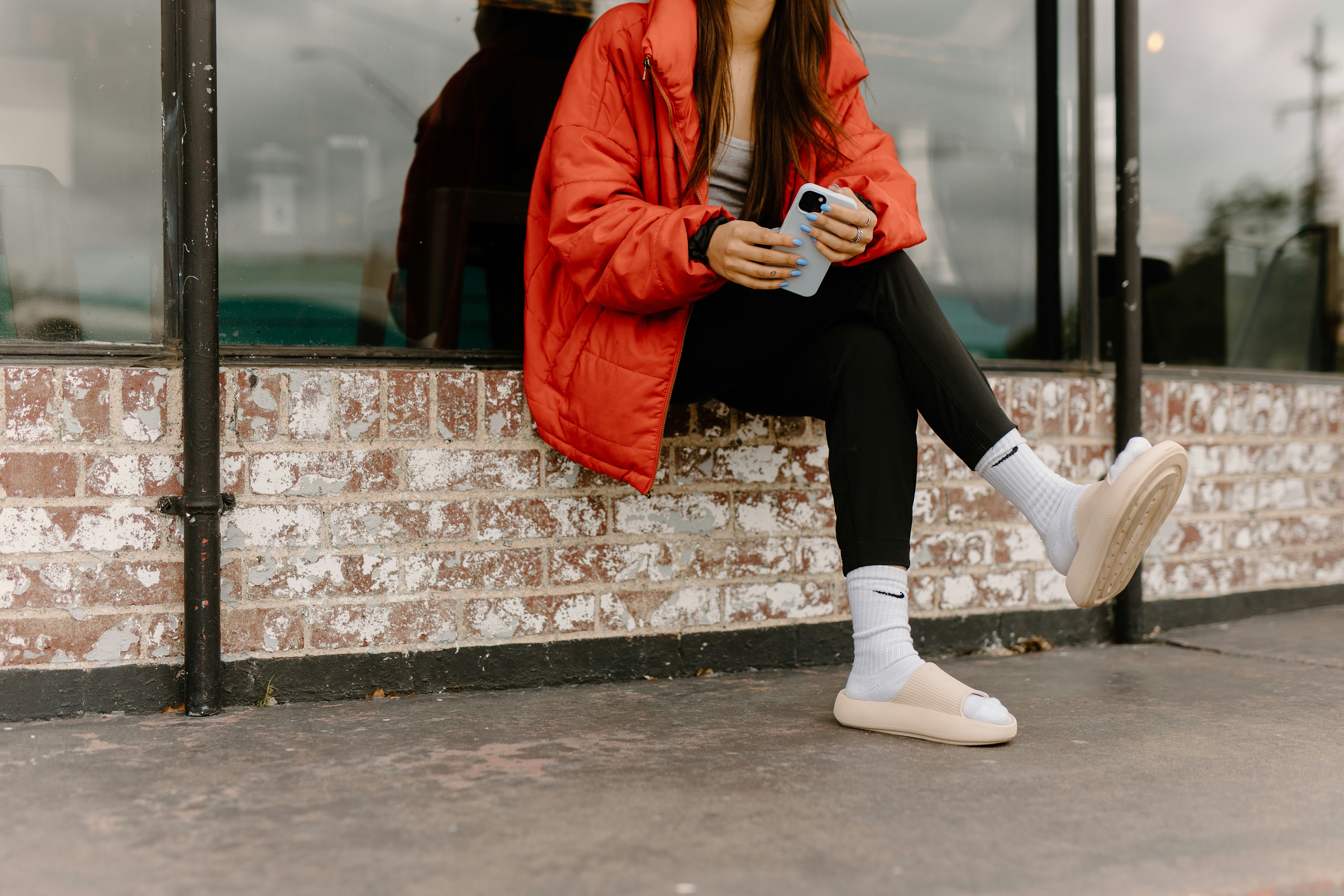 a woman sitting on a window sill looking at her cell phone