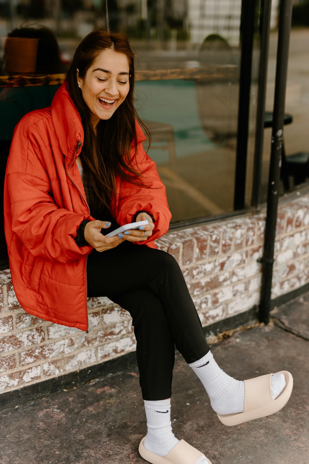 a woman sitting on a window sill looking at her cell phone