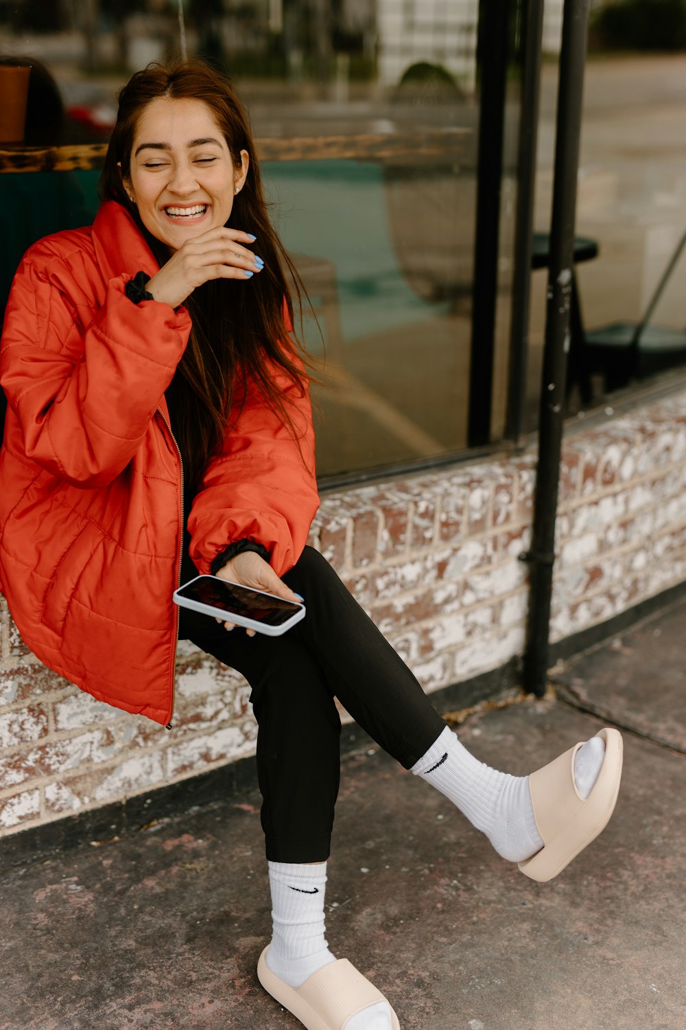 a woman in a red jacket sitting on a window sill